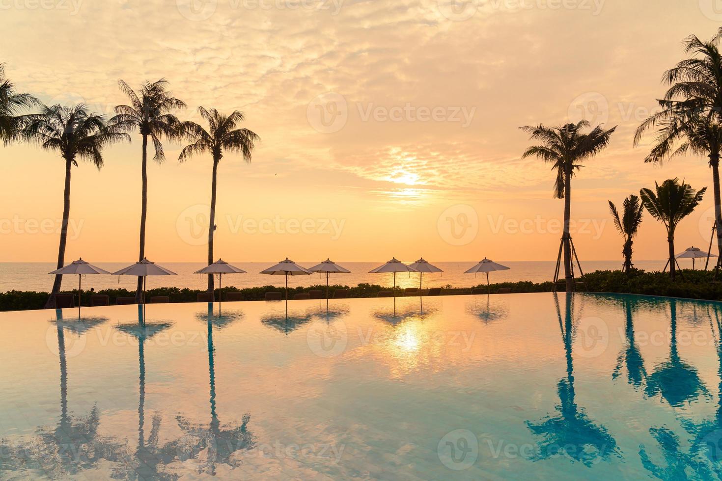 guarda-sol com cama piscina ao redor da piscina com fundo do mar oceano foto