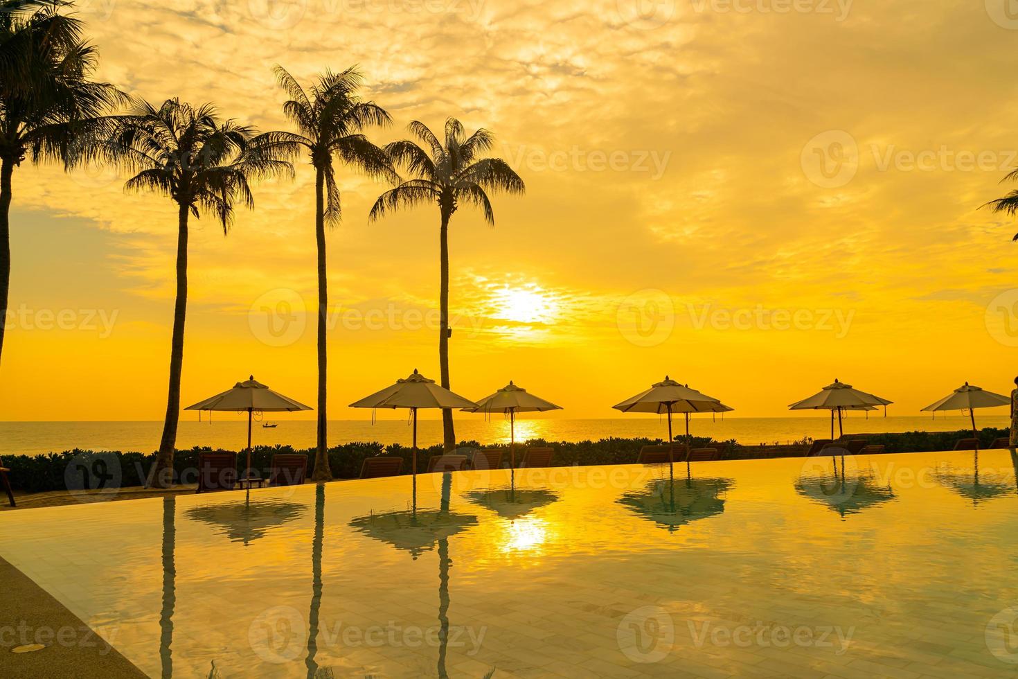 guarda-sol com cama piscina ao redor da piscina com fundo do mar oceano foto