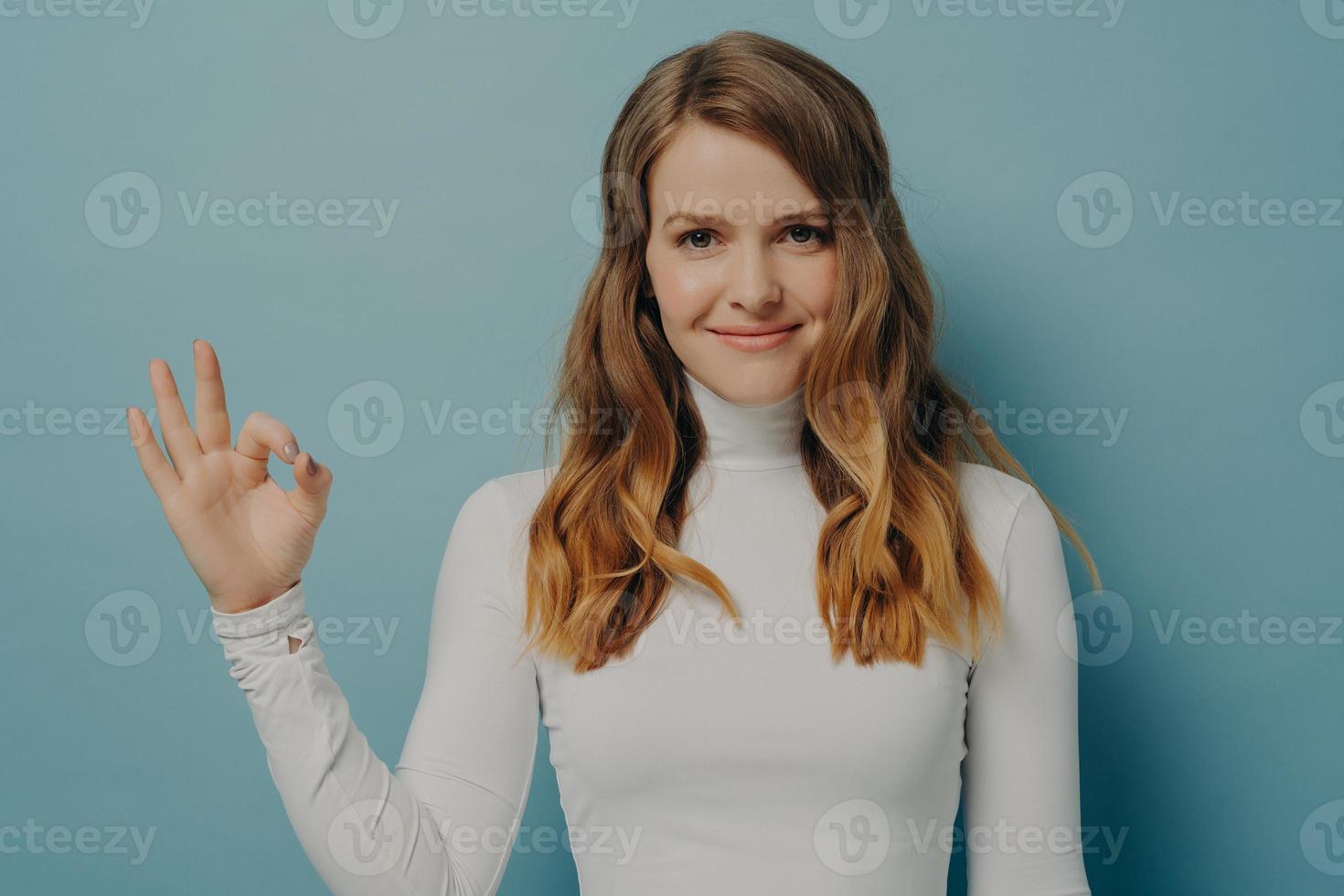 alegre jovem europeia mostrando o gesto bem isolado sobre a parede do estúdio azul pastel foto