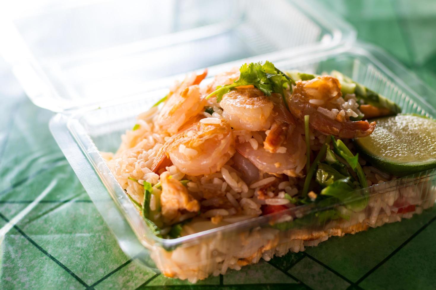 arroz frito coberto com camarão em uma caixa de plástico. foto
