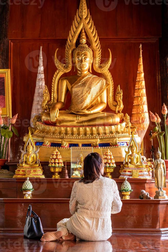 as costas da mulher se sentaram para prestar respeito à imagem de Buda. foto