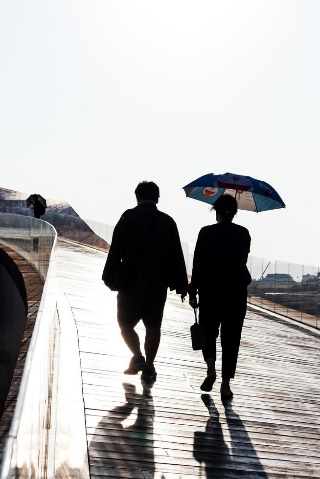 atrás das pessoas estendem um guarda-chuva para caminhar à luz do dia. foto