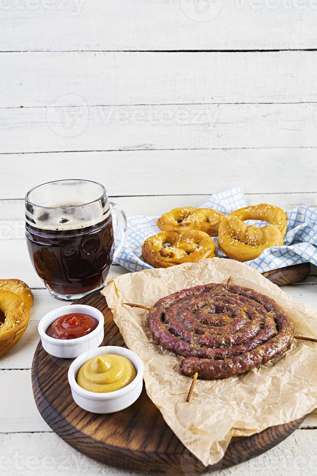 menu de comida para oktoberfest. salsicha com molho diferente, pretzel e copo de cerveja escura foto