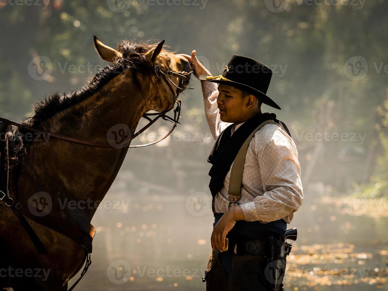 um jovem cowboy descansou com um cavalo no riacho depois que ele terminou de dar banho no cavalo foto