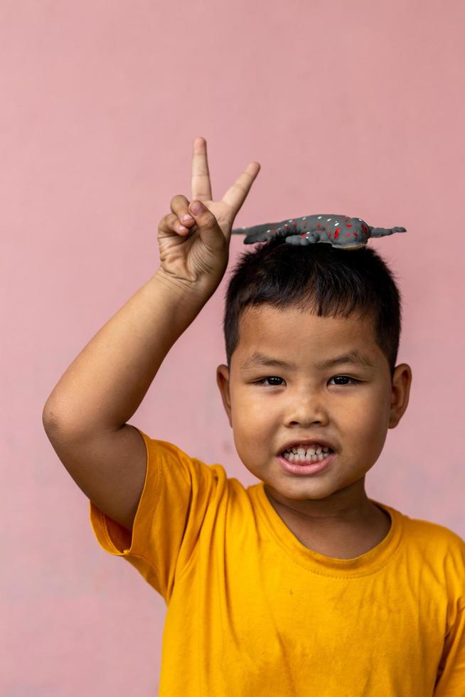 menino tailandês vestindo uma camisa amarela com lagartixa de borracha. foto