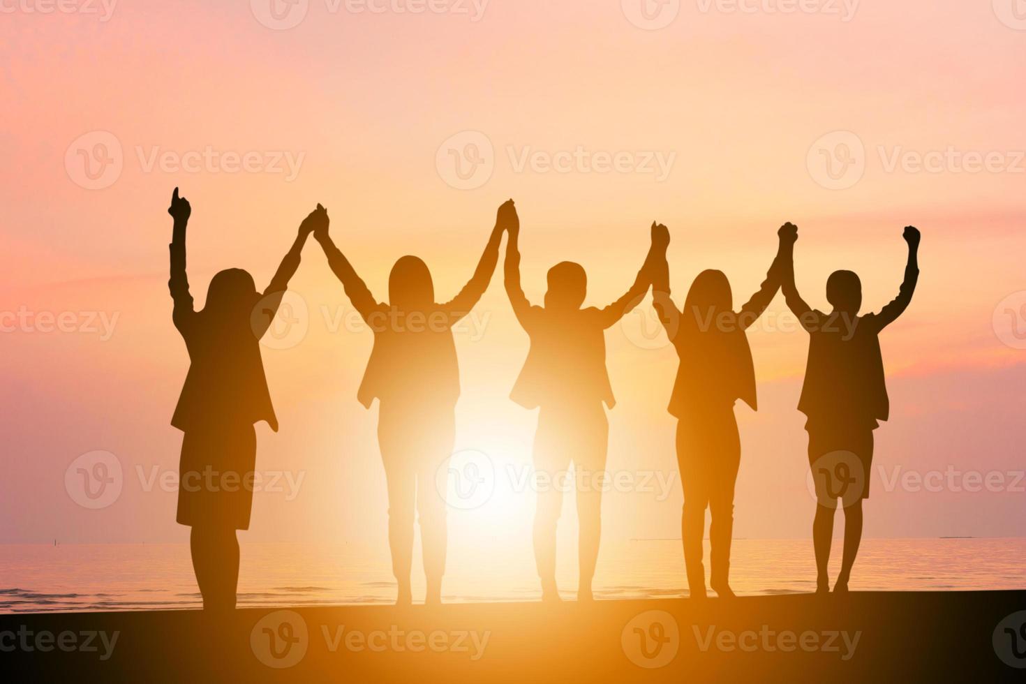 silhueta da equipe de felicidade de celebração de sucesso de mulher de negócios ao fundo do céu à noite por do sol foto