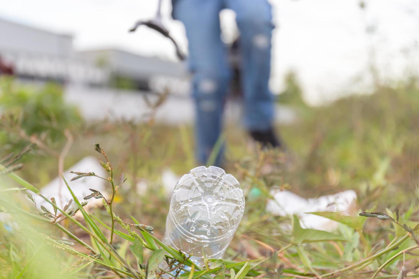 garrafa em um prado com turva o menino está coletando lixo no dia da noite, salve conceitos ambientais foto