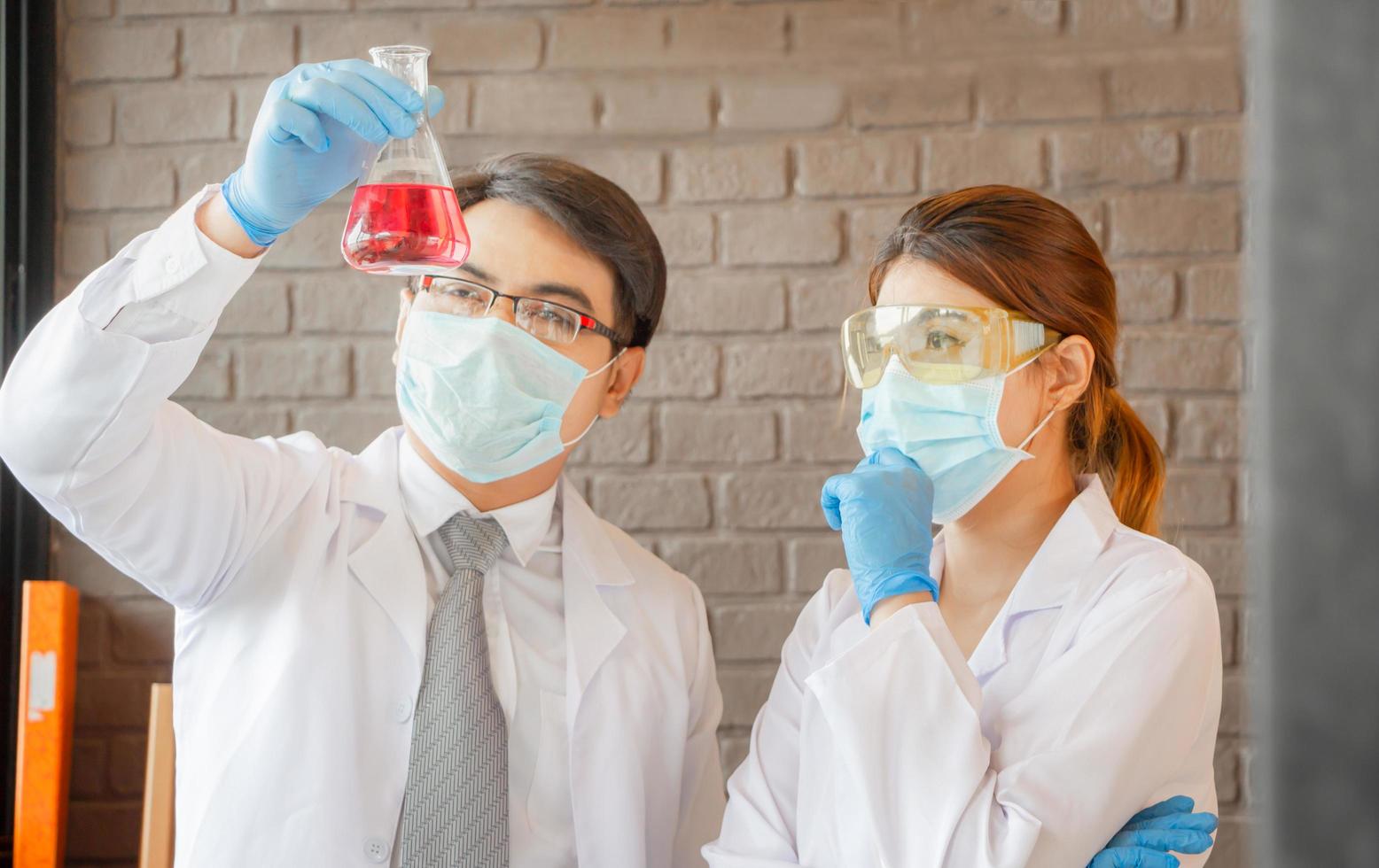 equipe de cientistas olhando para o tubo de ensaio fazendo pesquisa em laboratório clínico foto