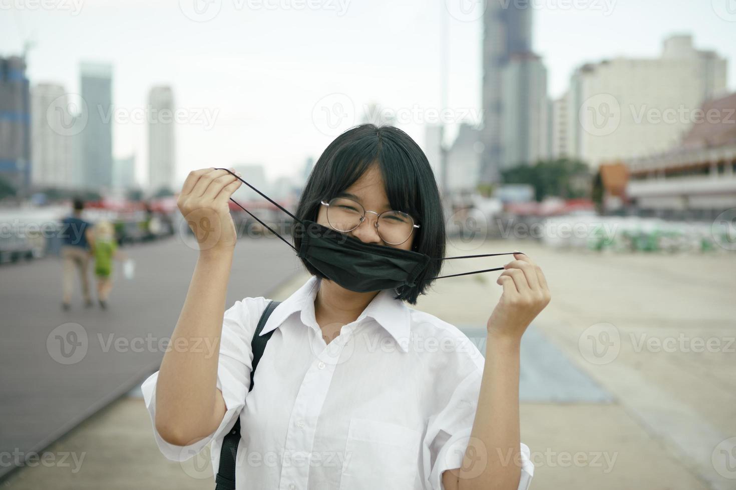 adolescente asiático com máscara facial de proteção na mão em pé ao ar livre foto