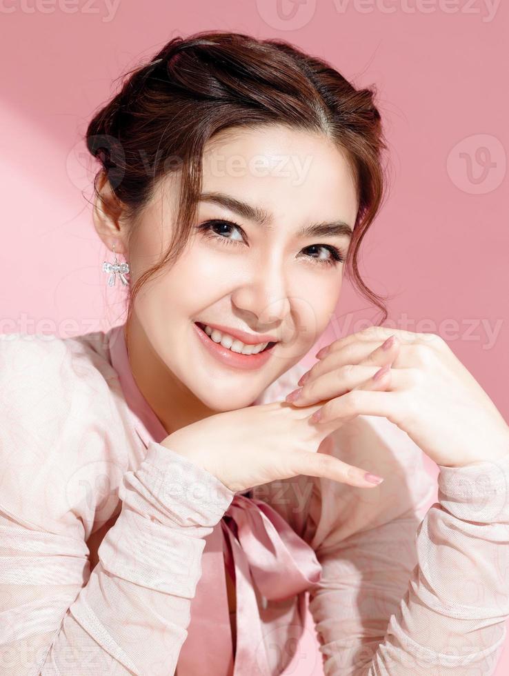 mulher asiática com um rosto bonito e pele fresca e lisa está vestida de rosa. foto