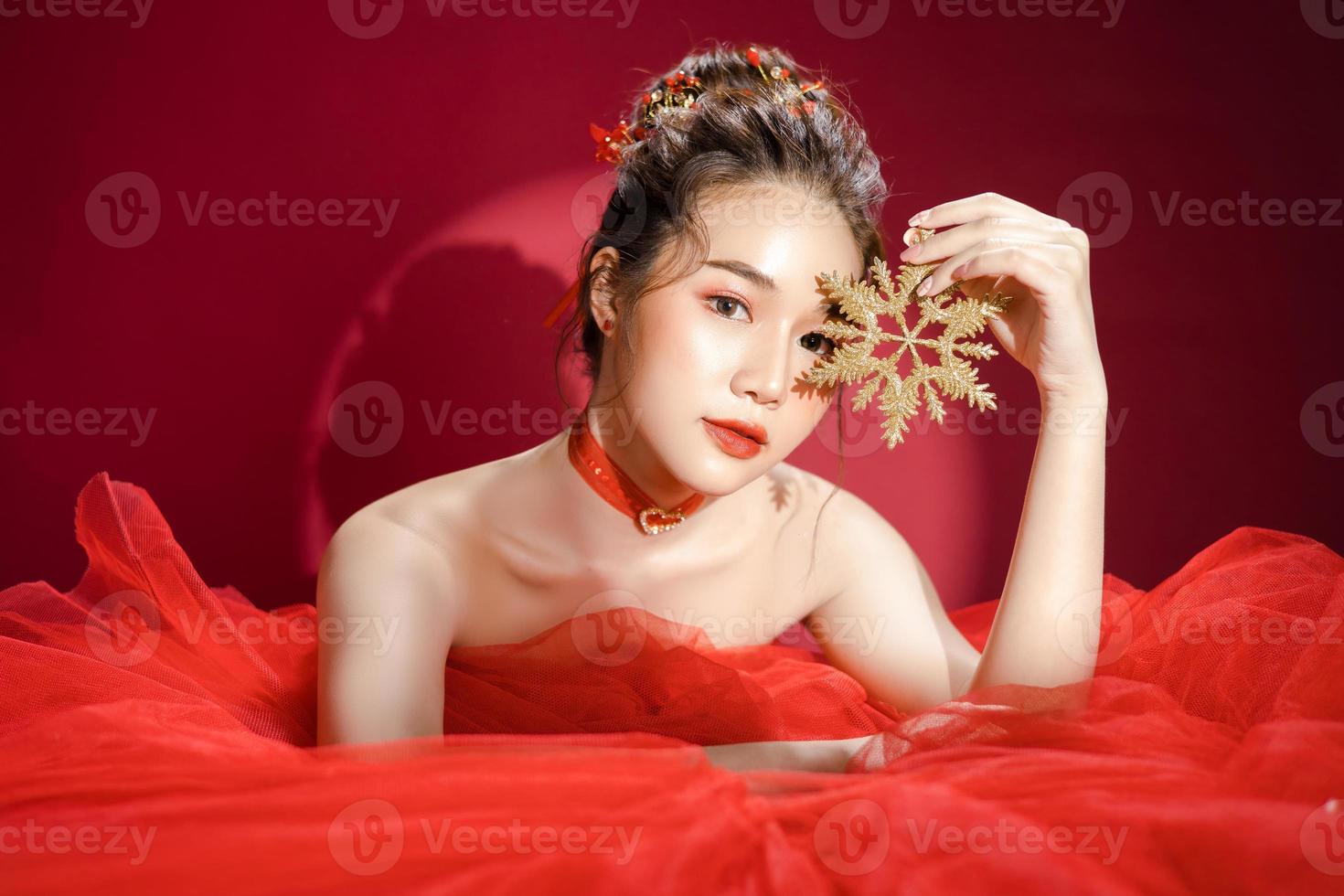 modelo de jovem mulher bonita asiática em um elegante vestido vermelho de luxo elegante sobre um fundo vermelho isolado. foto