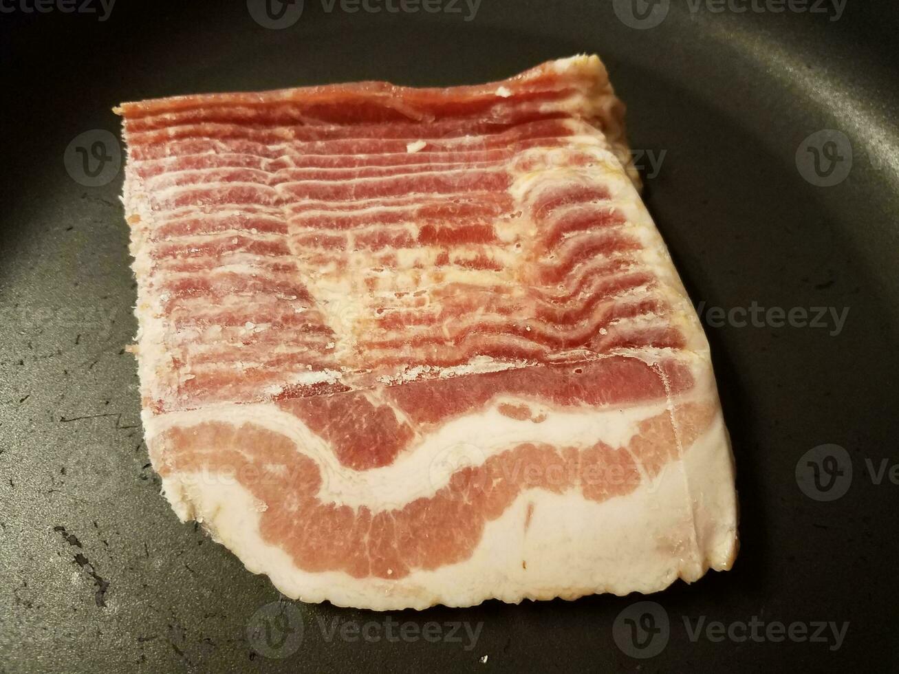 tiras de bacon cru congelado na frigideira ou frigideira foto