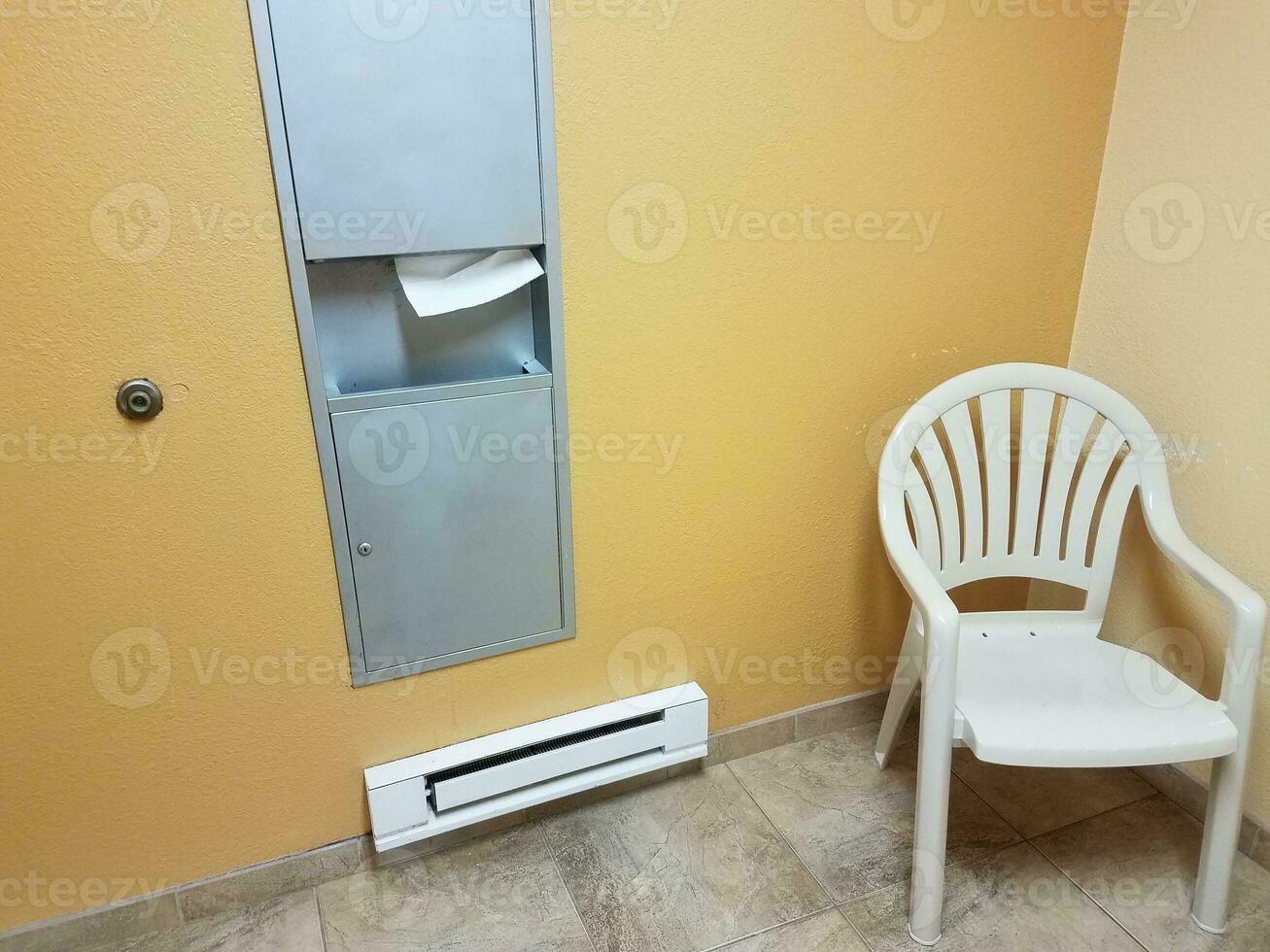 cadeira e aquecedor de piso e dispensador de papel toalha no banheiro foto