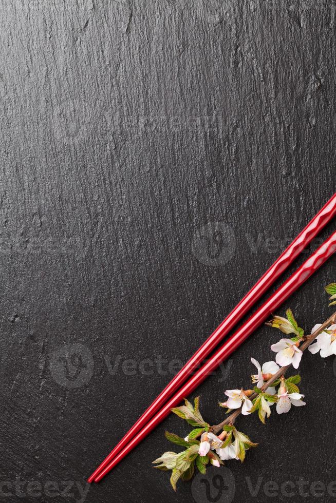 pauzinhos de sushi japonês e flor de sakura foto
