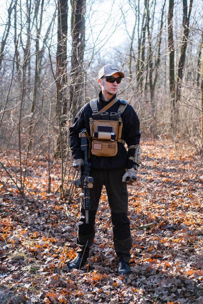 macho de empresa militar privada com rifle na floresta foto
