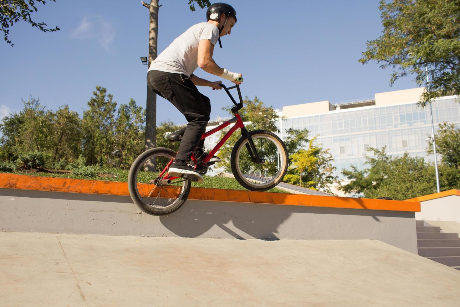 bmx rider treinando e fazendo truques na street plaza, bicyxle stunt rider em coccrete skatepark foto