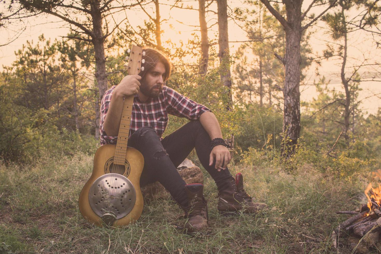 jovem macho com violão ao ar livre foto