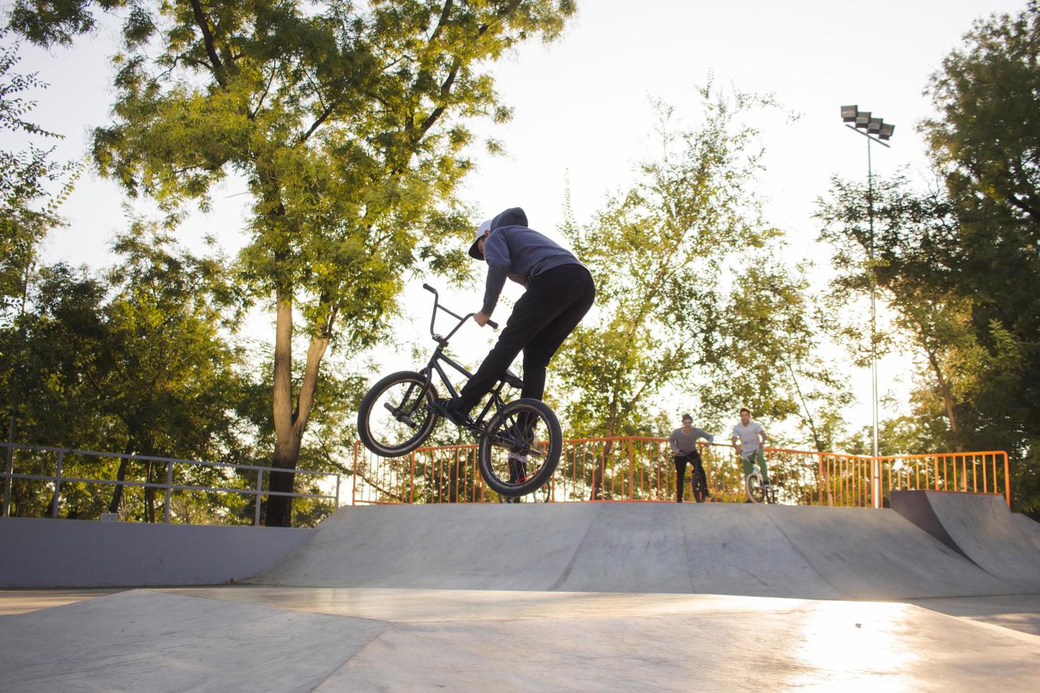 bmx rider treinando e fazendo truques na street plaza, bicyxle stunt rider em coccrete skatepark foto