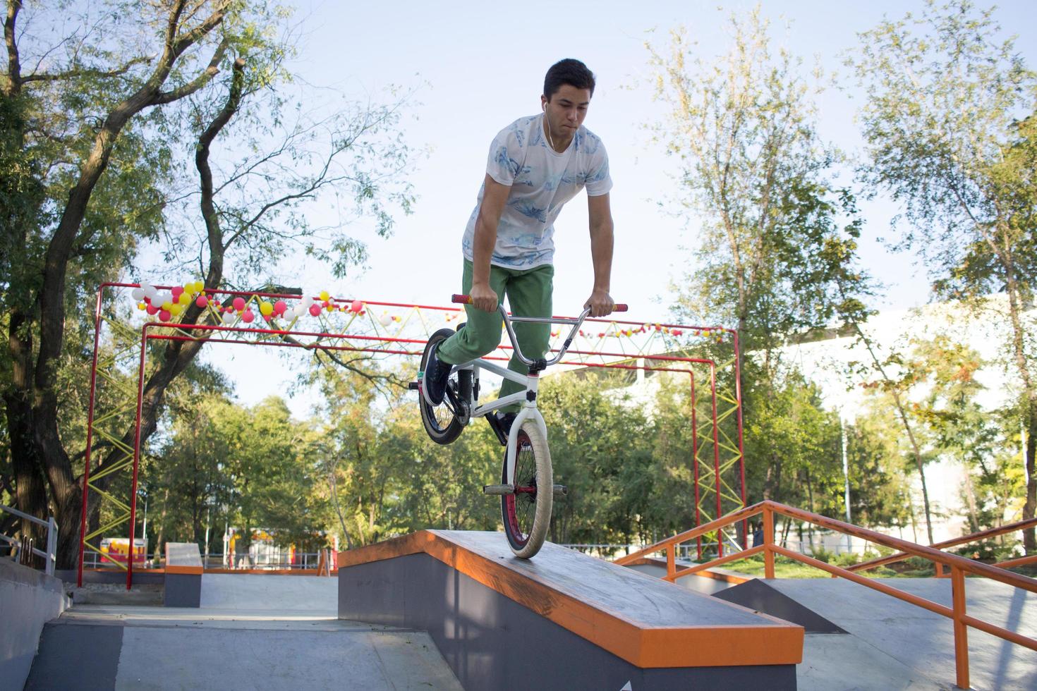 bmx rider treinando e fazendo truques na street plaza, bicyxle stunt rider em coccrete skatepark foto