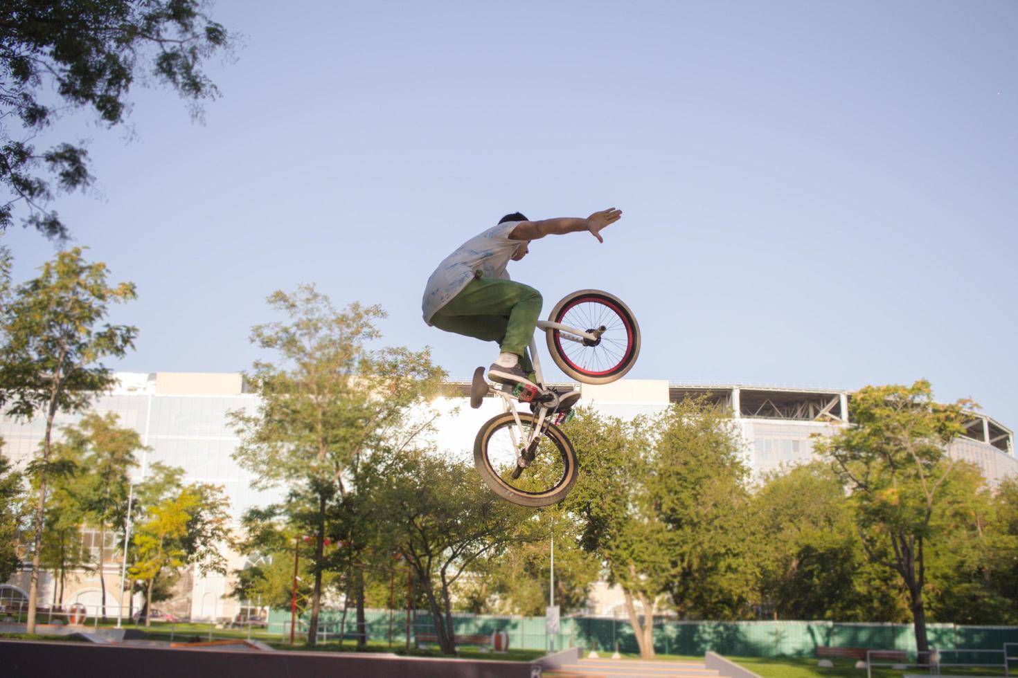 bmx rider treinando e fazendo truques na street plaza, bicyxle stunt rider em coccrete skatepark foto