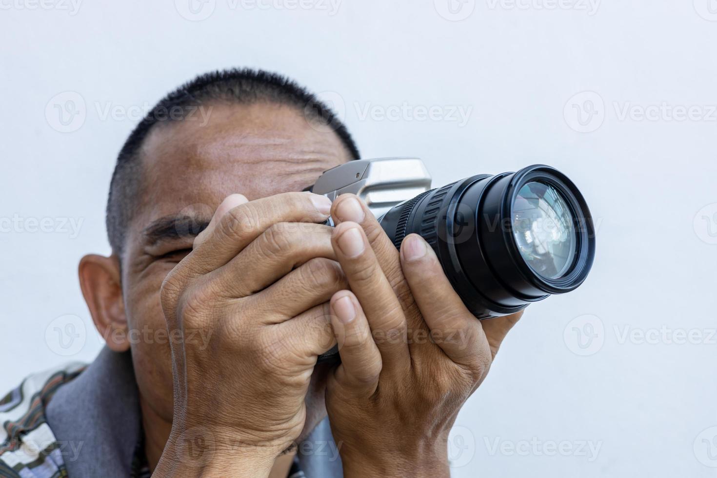 close-up isolado de um homem tailandês segurando uma grande câmera de filme dslr com uma lente de zoom preta. foto