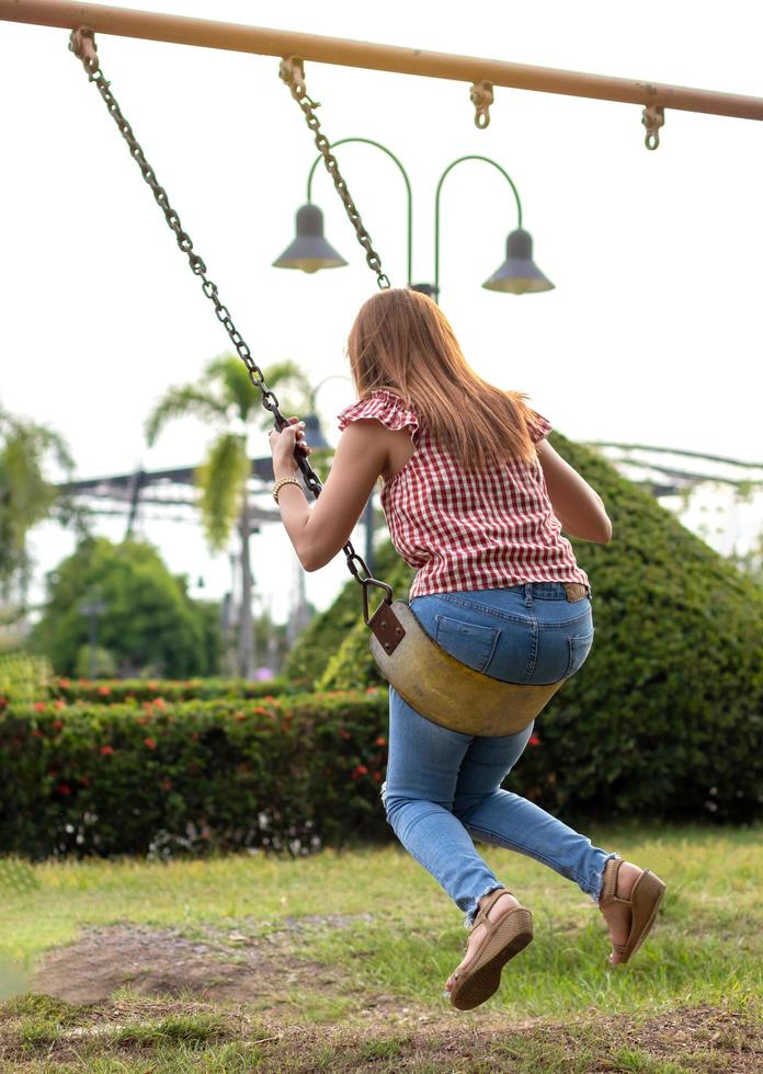 vista traseira de uma garota com um balanço no jardim. foto