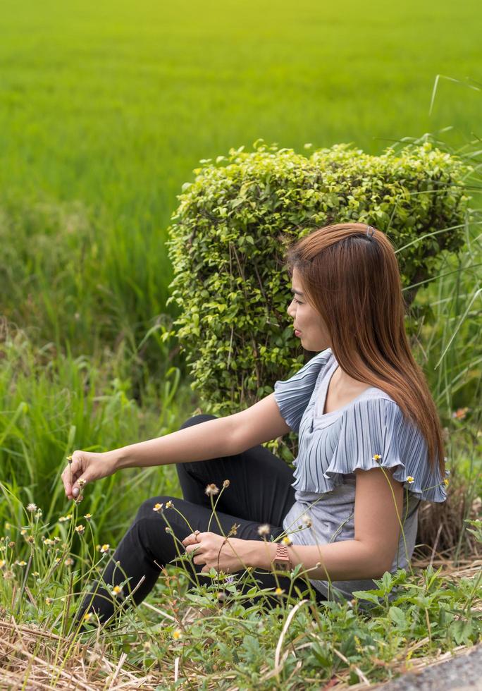 uma mulher tailandesa estava sentada na beira de uma estrada perto de um arbusto. foto