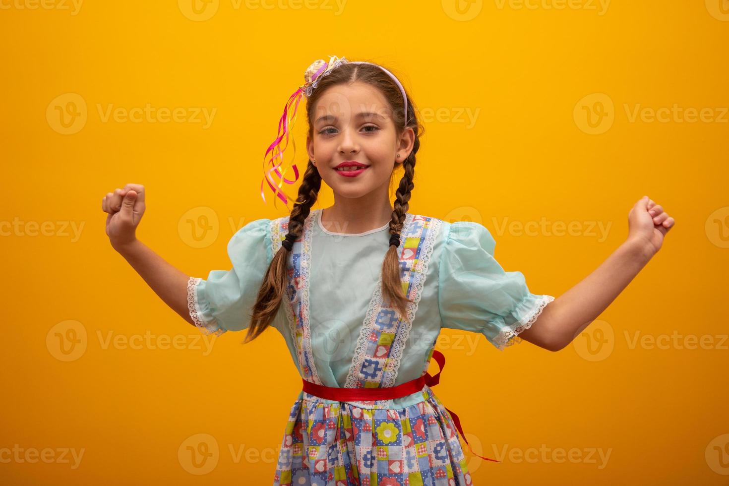 criança em roupas típicas da famosa festa brasileira chamada festa junina em comemoração a são joao. linda garota em fundo amarelo. foto