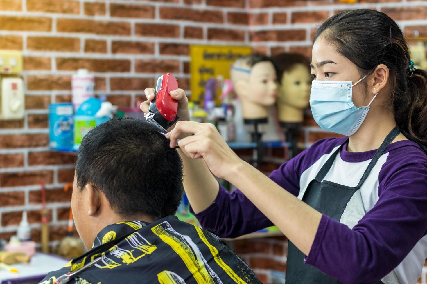 phichit, tailândia, 20 de julho de 2020 - mulher cortando cabelo masculino barbearia foto