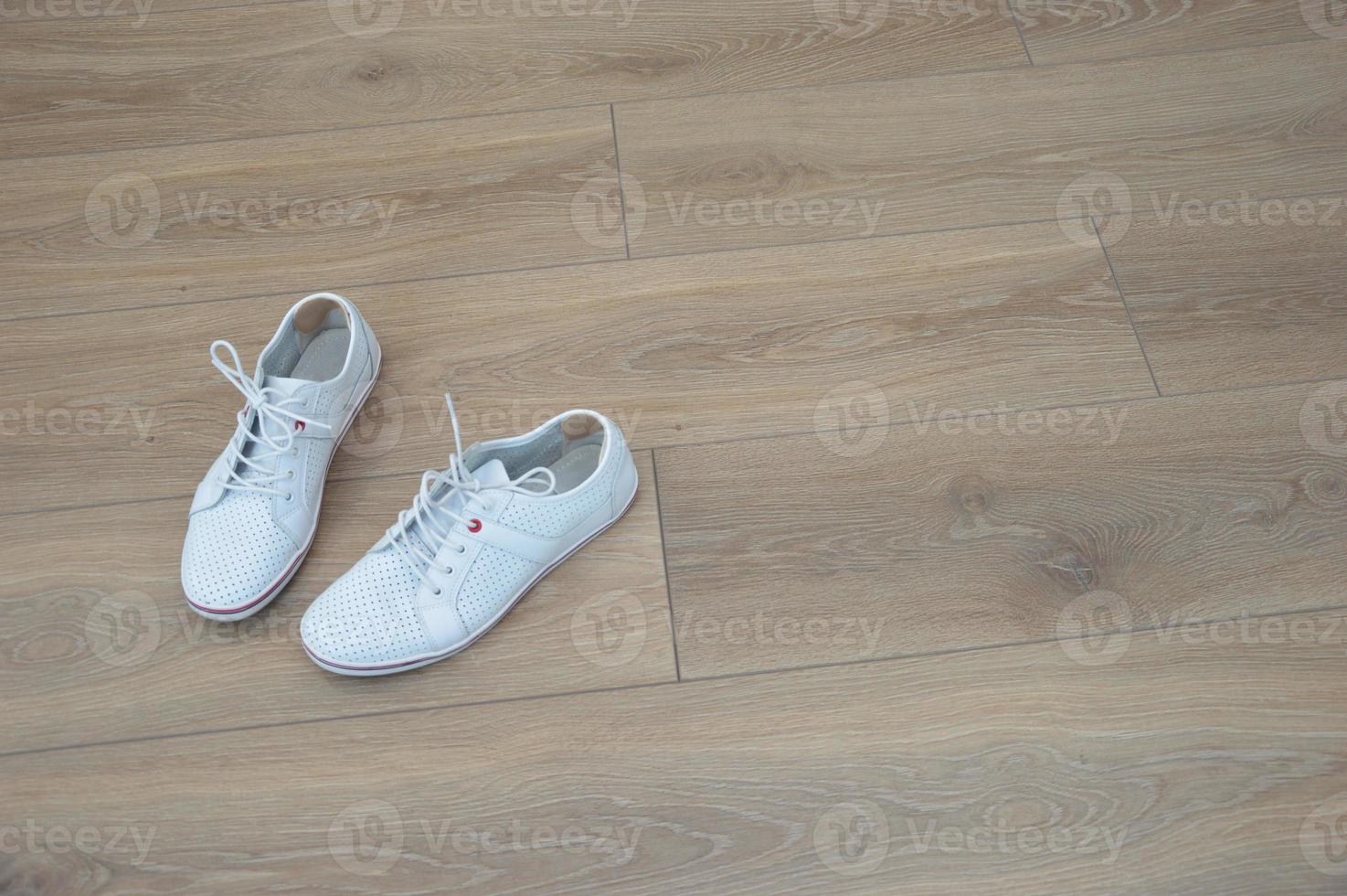 sapatos converse brancos para caminhar, caminhar, de pé sobre um piso de madeira marrom. adesivo anti-milho na parte de trás do calcanhar. foto