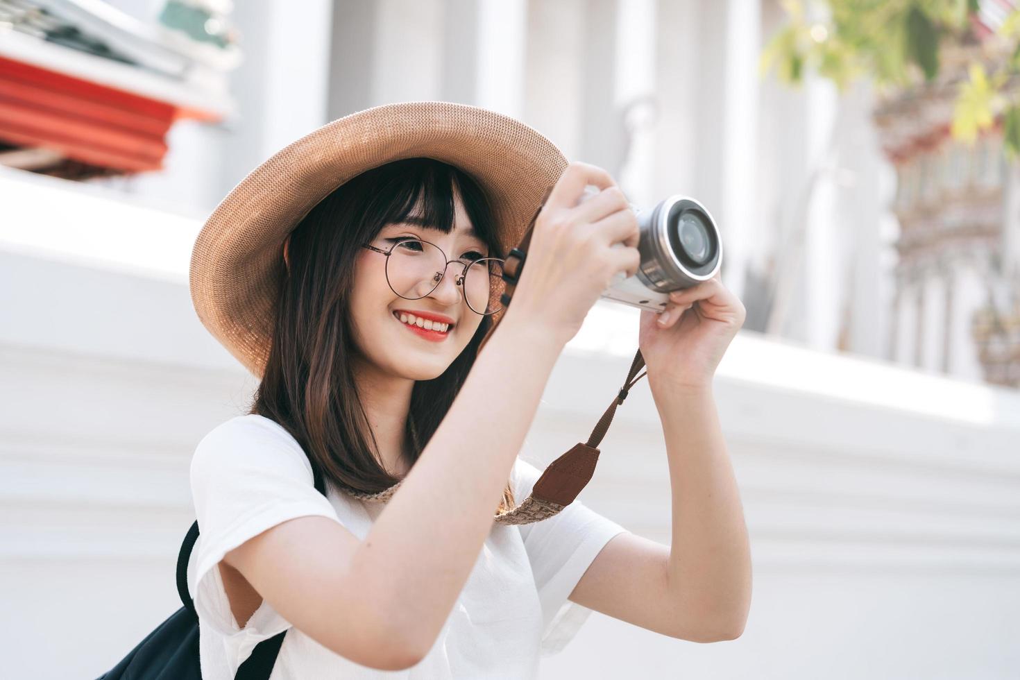linda garota asiática usa câmera para tirar foto no templo. Bangkok, Tailândia.