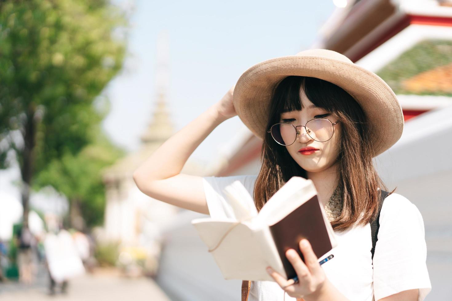 jovem asiático óculos bonito adolescente menina viajante mochila solo viagem local com memorando escrito diariamente. foto
