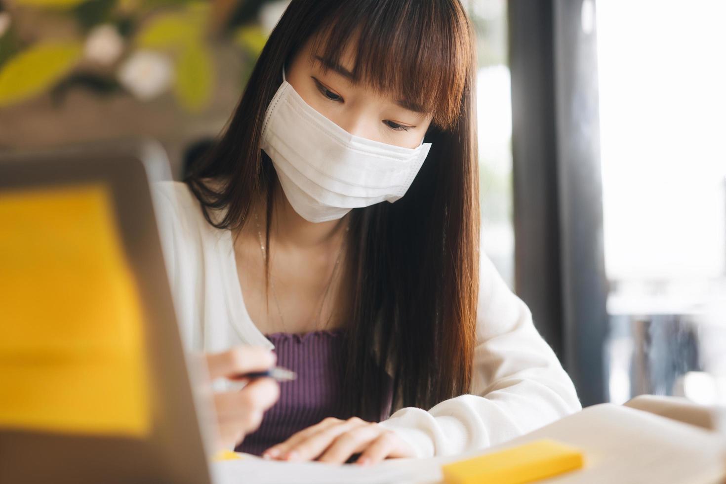 jovem mulher asiática adulta com máscara facial protetora trabalha e estuda no café novo estilo de vida normal. foto