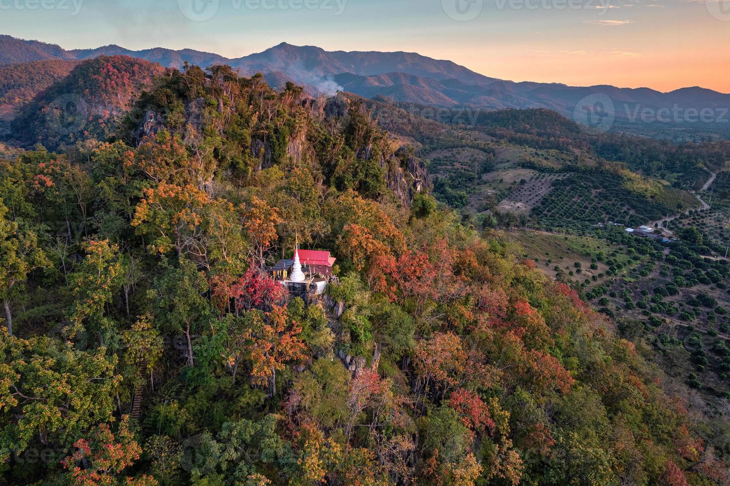 vista aérea do pagode branco na montanha com folhagem colorida na floresta de outono à noite foto