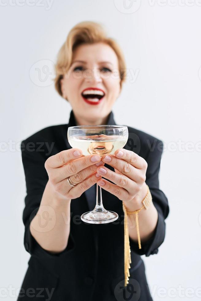 mulher elegante elegante madura de smoking com copo de vinho espumante. festa, celebração, conceito anti-idade foto