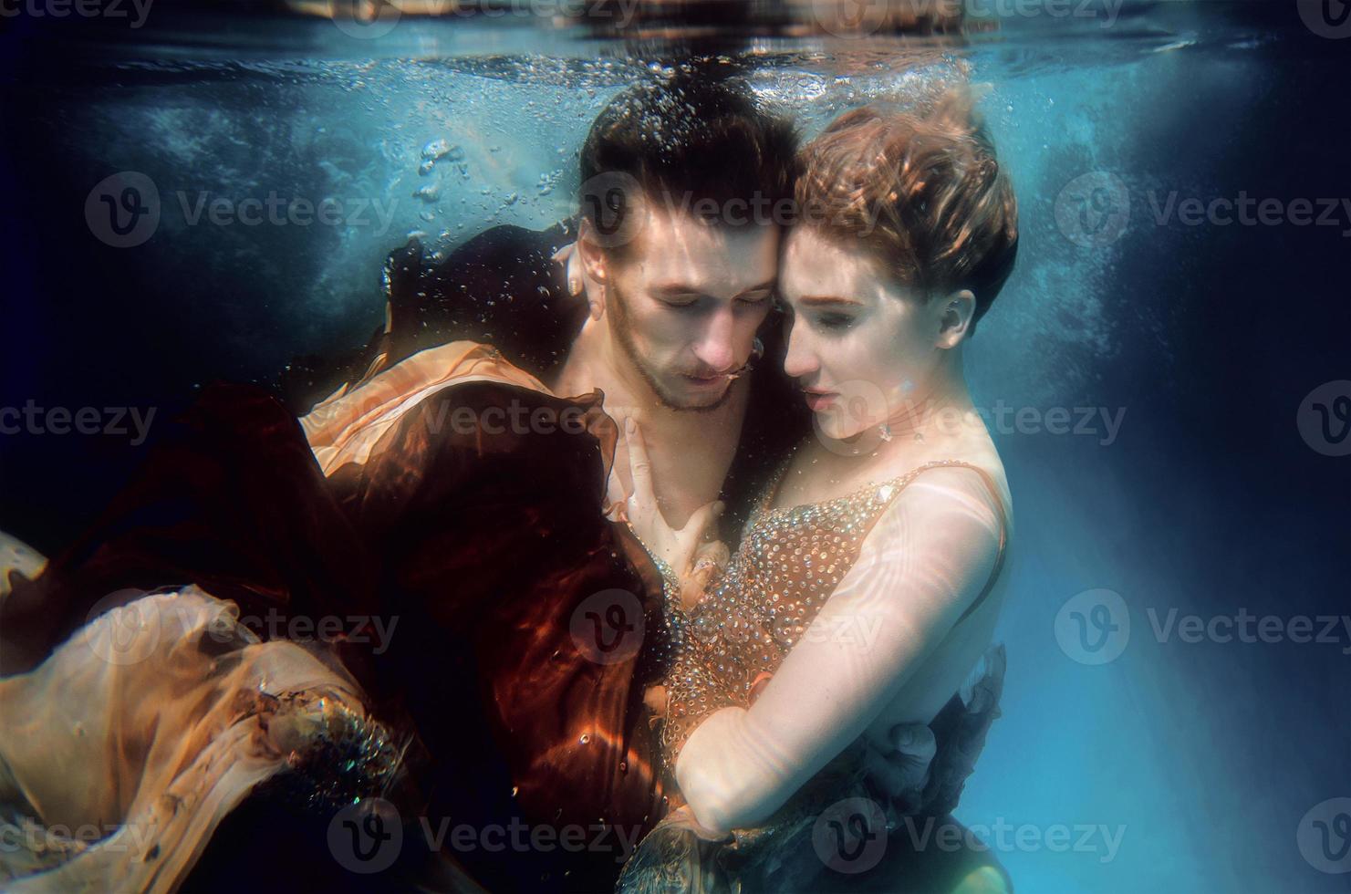 lindo casal dançando debaixo d'água na piscina foto