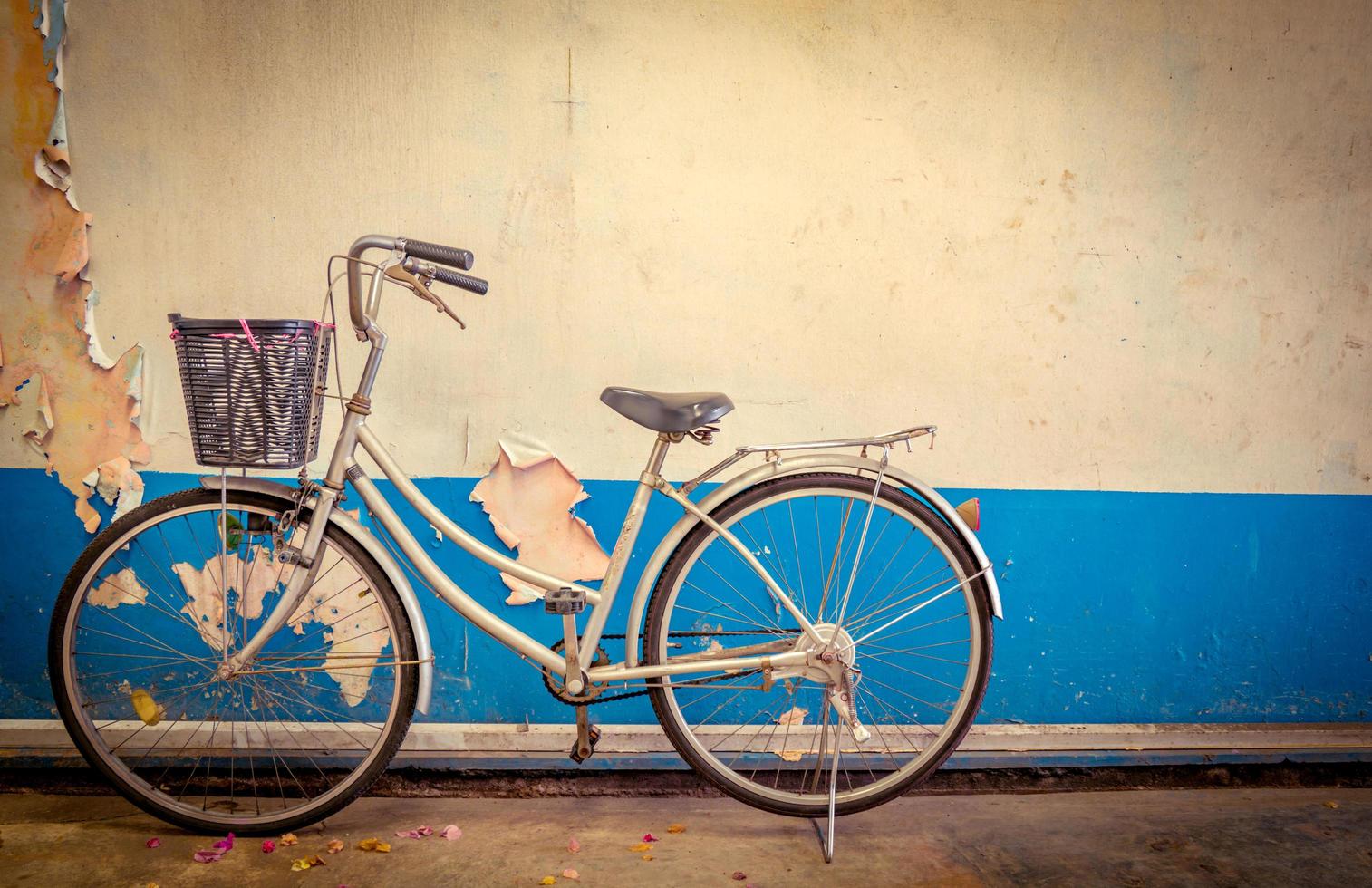 a bicicleta estacionada ao lado das velhas paredes de cimento pintadas de branco e azul. foto