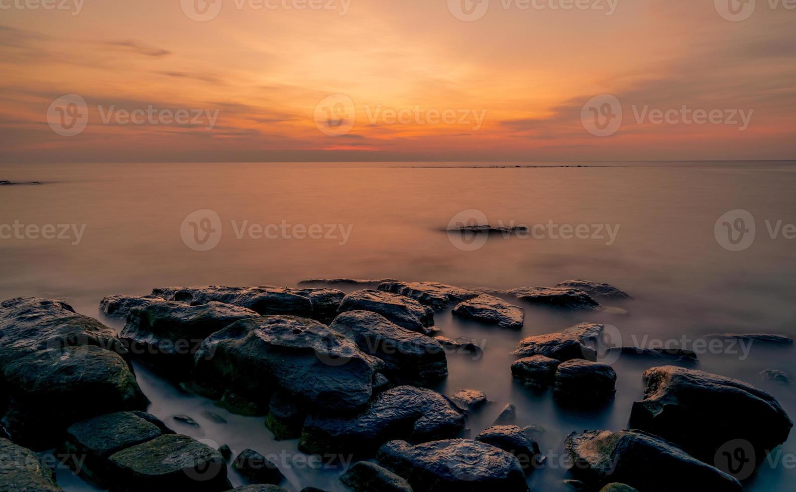 rochas na praia de pedra ao pôr do sol. lindo céu do sol da praia. mar e céu crepusculares. mar tropical ao entardecer. céu dramático e nuvens. abstrato por do sol. acalme e relaxe a vida. paisagem da natureza. foto