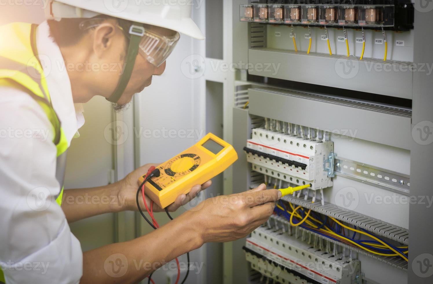 os engenheiros elétricos testam a tensão e a corrente dos fios no controle do gabinete elétrico. o multímetro está nas mãos dos detalhes do eletricista. foto