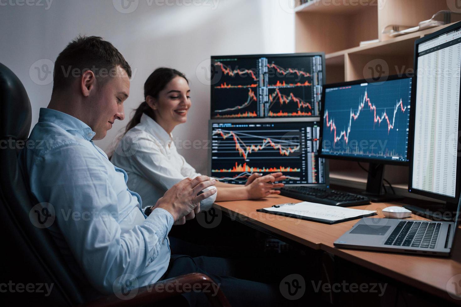 equipe de corretores da bolsa está conversando em um escritório com várias telas de exibição foto