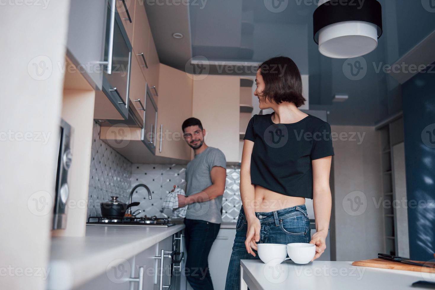 olhando um para o outro. jovem casal na cozinha moderna em casa no fim de semana pela manhã. foto