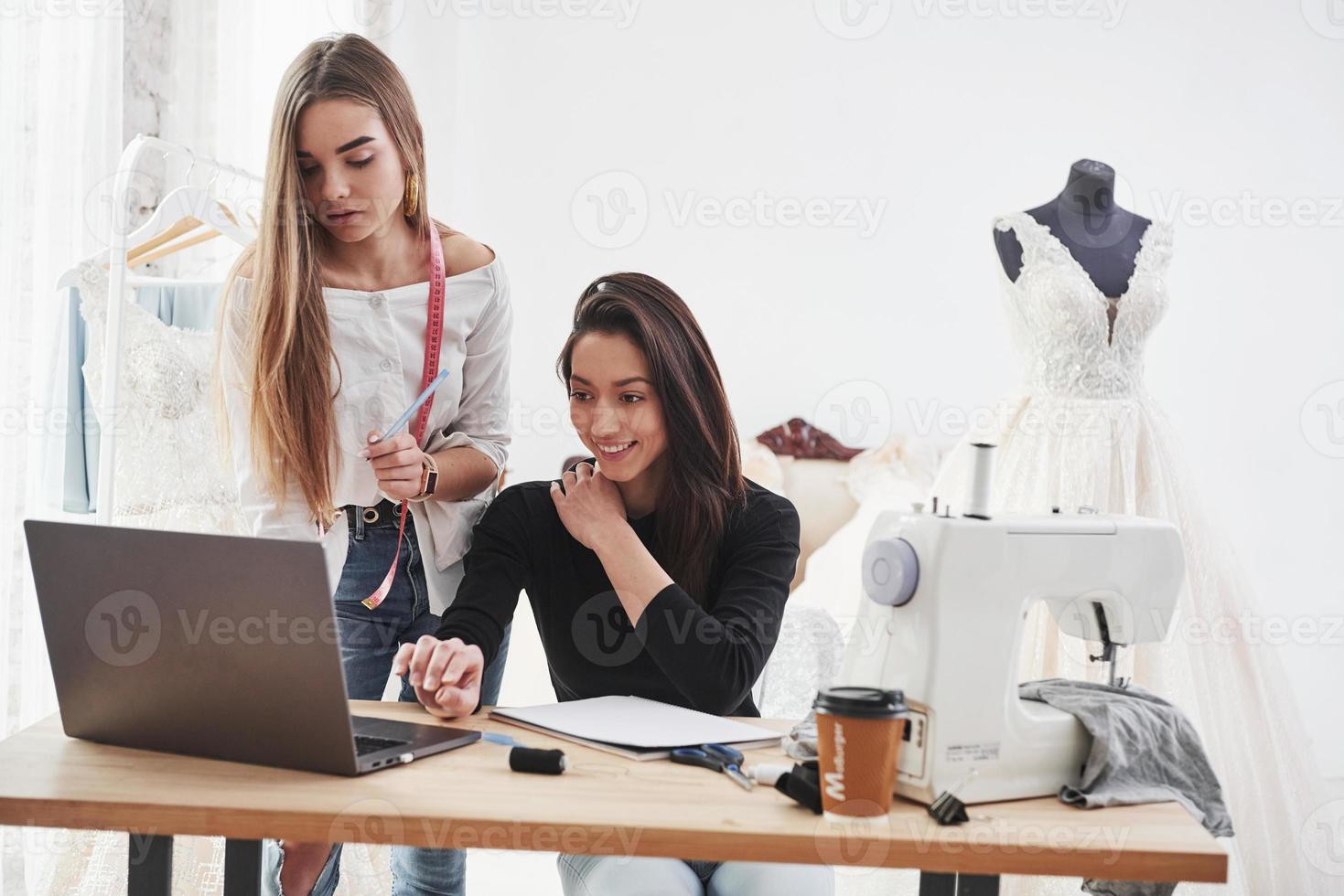 eu tenho mensagem com novo pedido. duas estilistas femininas trabalham nas novas roupas na oficina foto