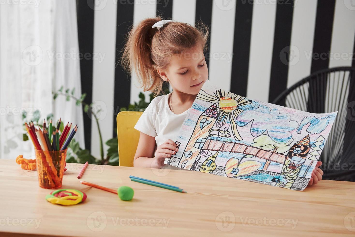 ela será pintora profissional um dia. menina bonitinha na escola de arte mostra sua primeira foto desenhada por lápis e marcadores