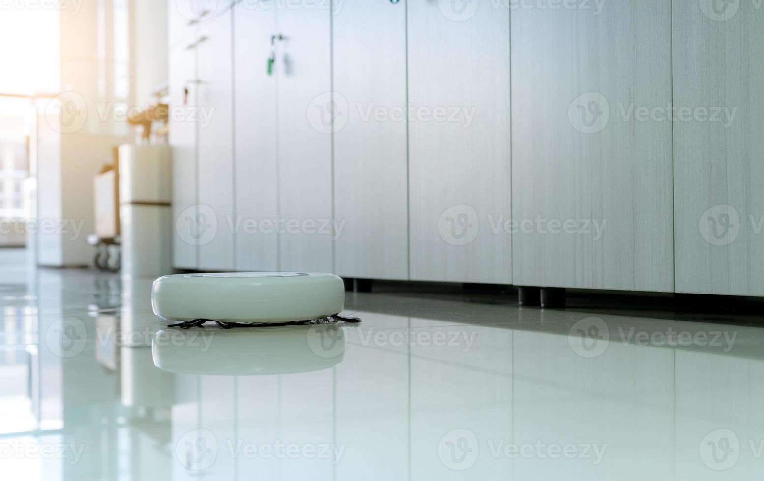 robô aspirador de pó limpando o chão no escritório. aspirador de pó robô branco para o conceito de casa inteligente. robô de limpeza para limpeza de piso. dispositivo wireless. tecnologia de limpeza inteligente. aparelho doméstico. foto