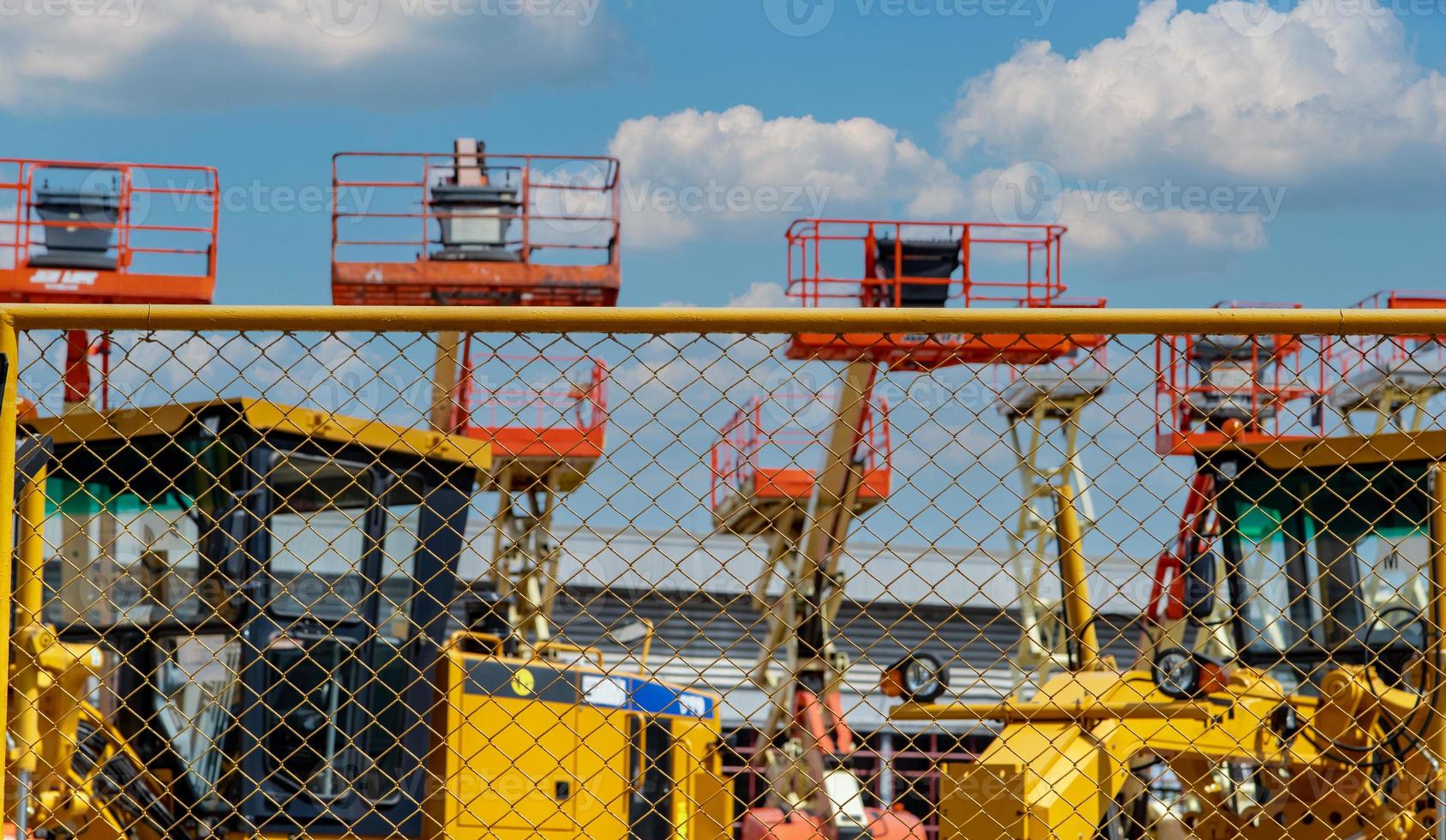 cerca de malha de estacionamento de armazém ao ar livre de elevador de lança articulada e motoniveladora. máquina para locação na indústria de construção e mineração. blur guindaste de construção e motoniveladora para alugar. foto