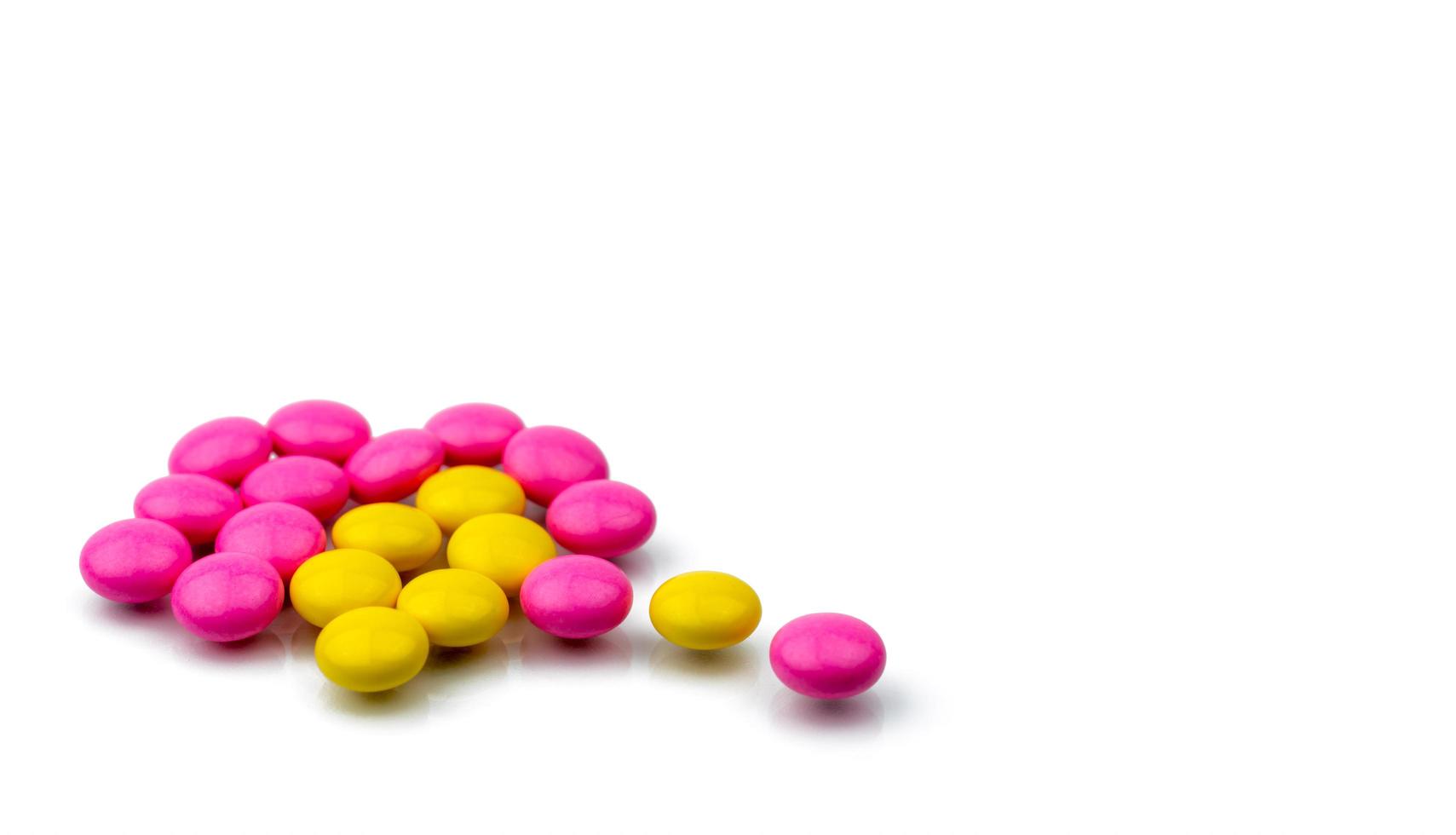 pilha de comprimidos revestidos de açúcar redondo rosa e amarelo isolados no fundo branco com espaço de cópia. pílulas coloridas para tratamento anti-ansiedade, antidepressivo e profilaxia de dor de cabeça de enxaqueca. foto