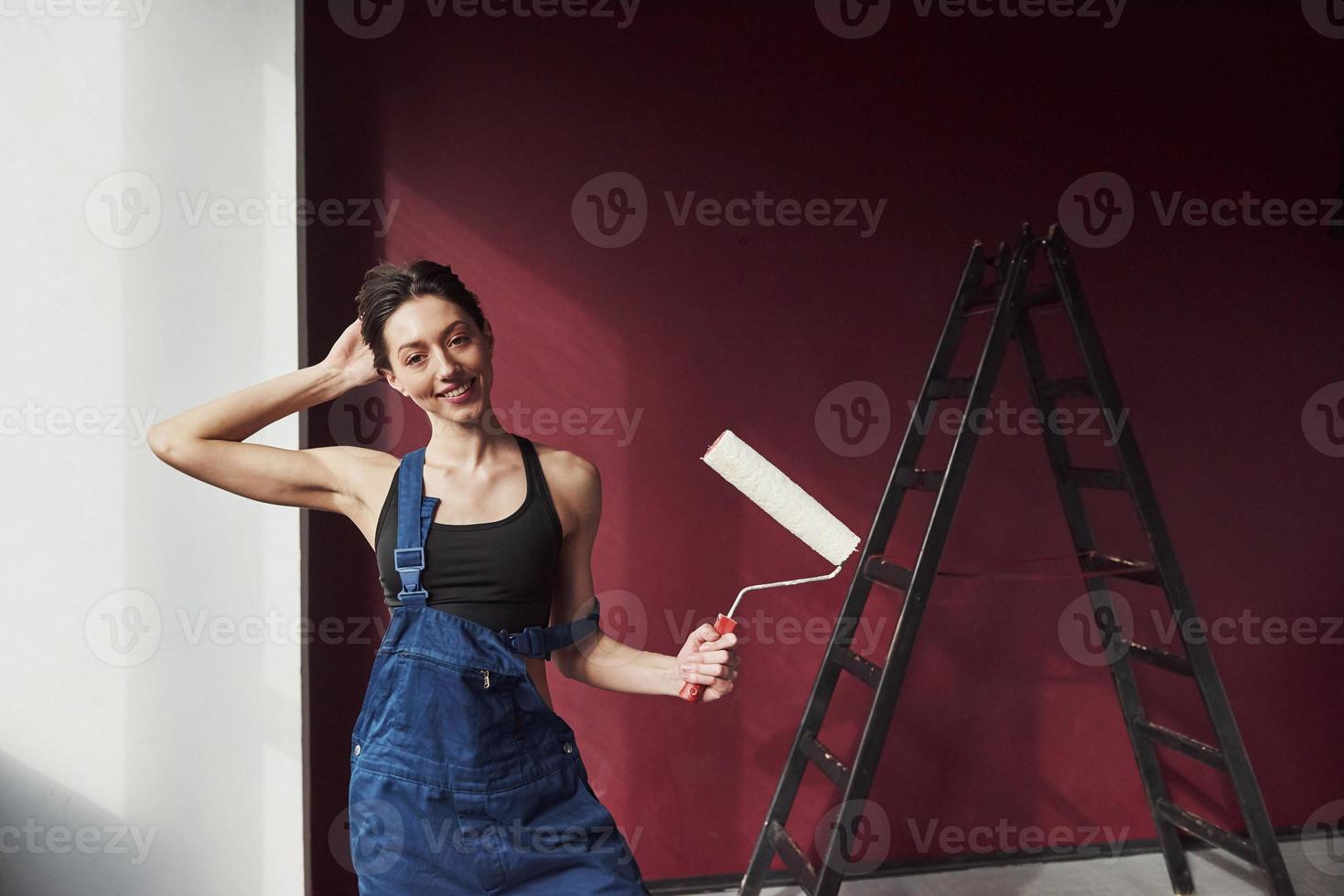 dia de trabalho chegou. jovem dona de casa decidiu colar papel de parede em sua nova casa no quarto foto