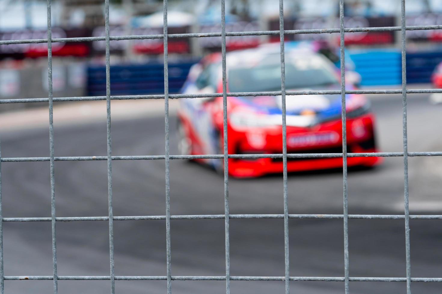 corridas de carros de automobilismo na estrada de asfalto. vista da rede de malha de vedação no carro turva no fundo da pista. super carro de corrida no circuito de rua. conceito de indústria automotiva. foto