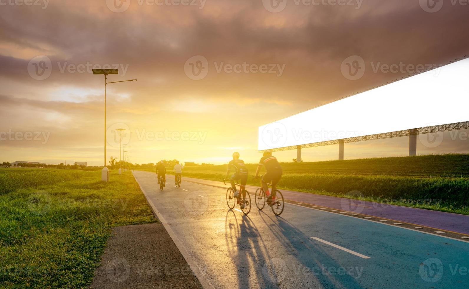 homem de esportes andar de bicicleta na estrada à noite perto de outdoor publicitário em branco com céu pôr do sol. exercício ao ar livre de verão para uma vida saudável e feliz. ciclista andando de bicicleta de montanha na ciclovia. foto