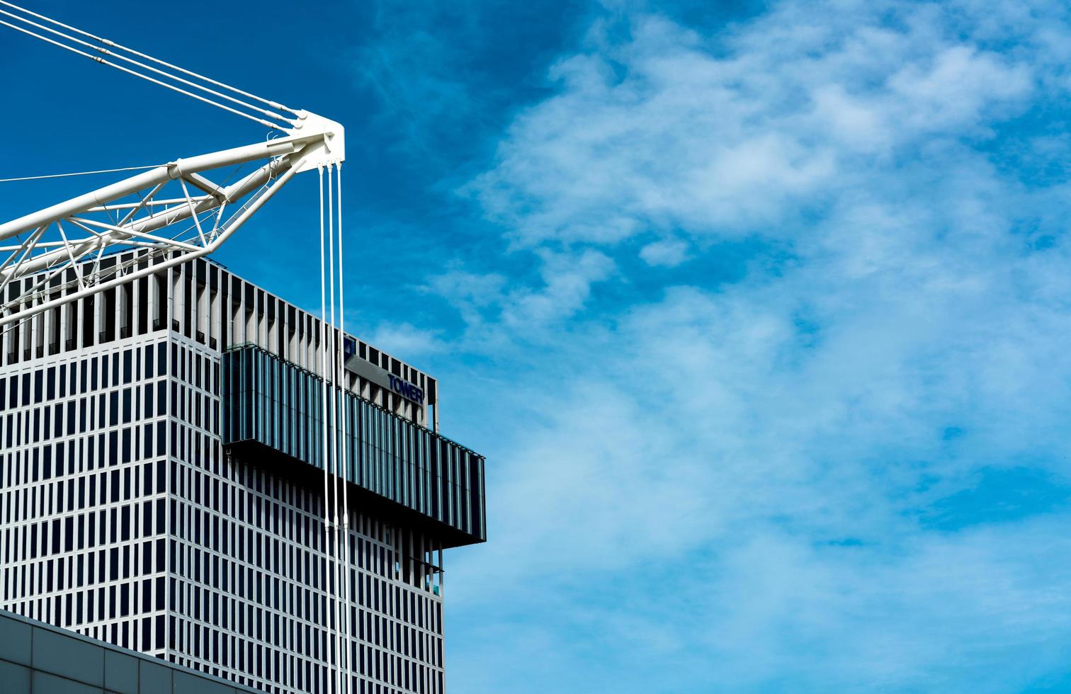 edifício do escritório perto do canteiro de obras e céu azul e nuvens brancas. construção de torre de negócios da empresa foto